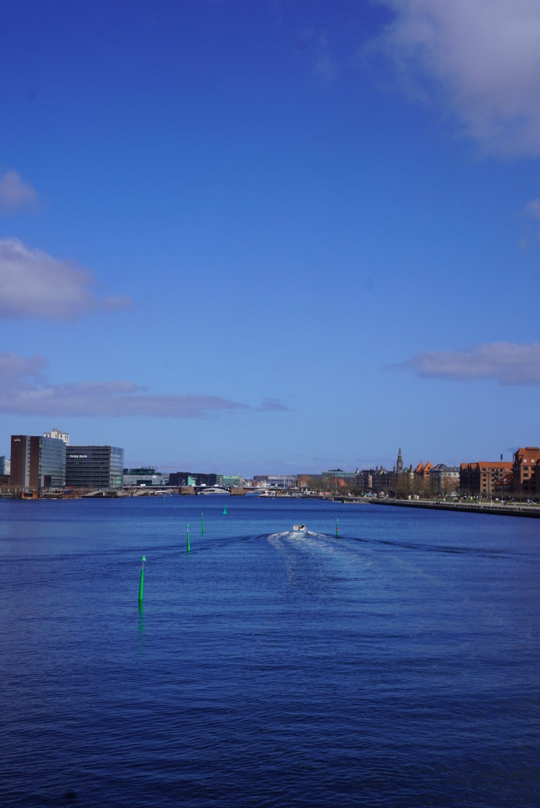 Copenhagen harbour, a boat cutting through blue water.