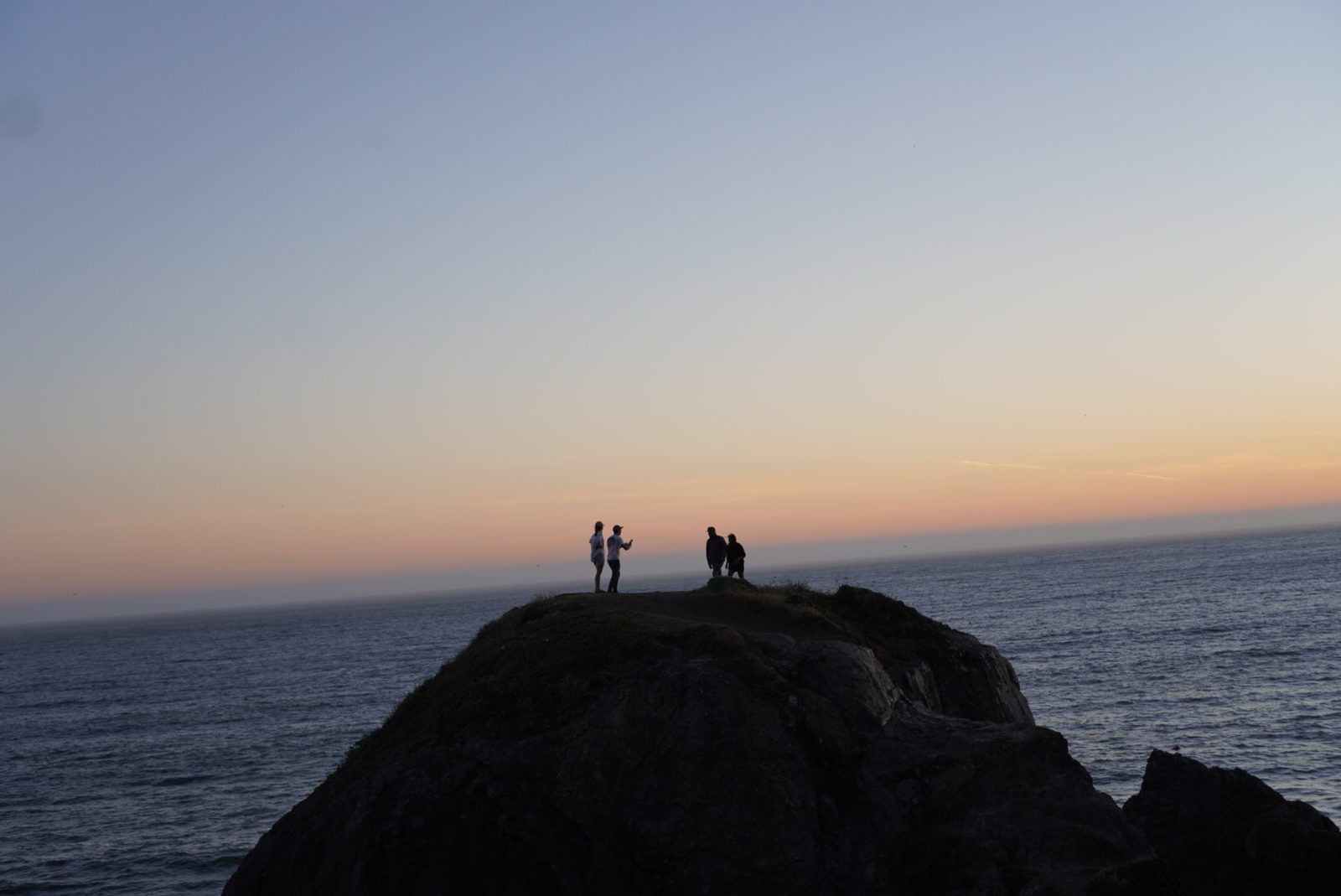 Figures silhouetted on a California headland at sunset.